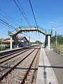 Photographie en couleurs, représentant une passerelle et une voie ferrée.