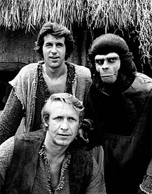 Trois hommes dont l'un déguisé en singe.