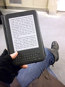 Reading an e-book on a third-generation Kindle Reading on the bus train or transit.jpg