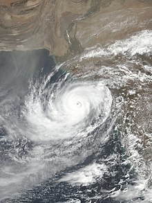 A satellite image of a strong tropical cyclone with a distinct eye evident amid a circular disc of clouds.