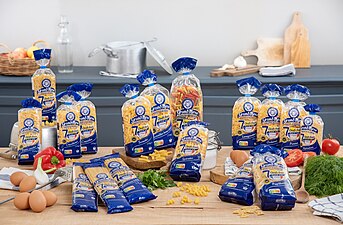 Photographie présentant des paquets de pâtes alimentaires estampillés « Grand'Mère » au milieu d'autres produits alimentaires.