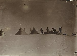 Bilden, som är anfrätt av tiden, visar flera tält i djup snö. Kring tälten syns människofigurer. De är deltagarna i expeditionen.