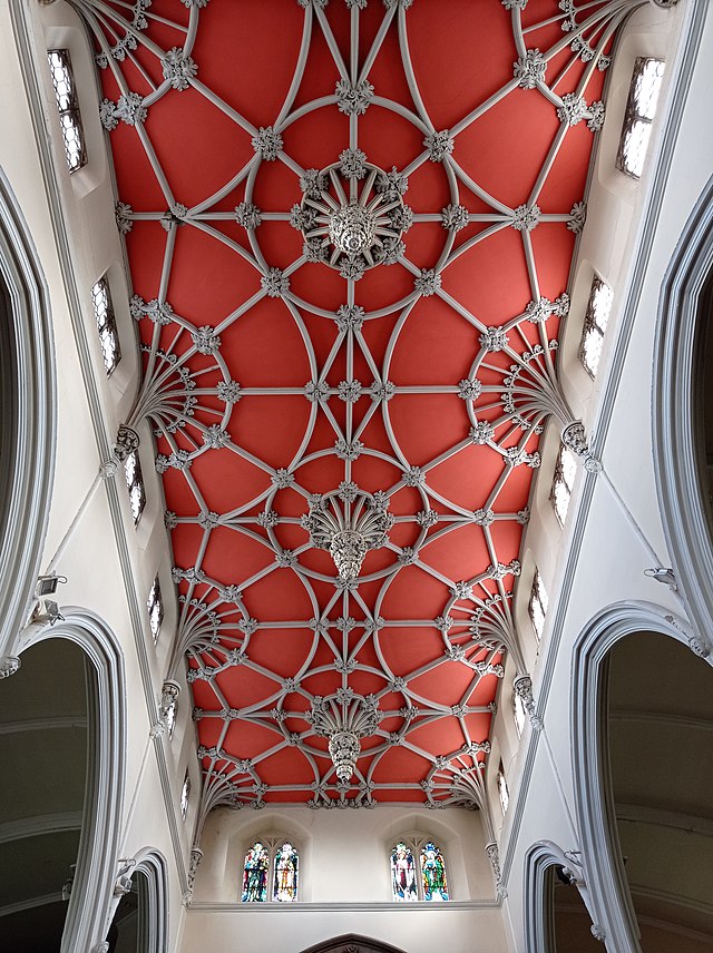 An ornate church ceiling with stone ribs on a red ground