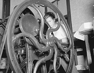 1937 photograph of a printing press with a man operating it