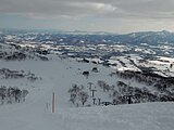 ゲレンデ「ワンダーランド」からワンダーランドチェア（中央→右下）、カントリーロードチェア（中央→奥）、旧・東山ゴンドラ山頂駅（左上）を望む（2022年2月撮影）