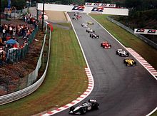 Mika Häkkinen, the first black and silver car, leads a field of ten Formula One cars on a wet track.