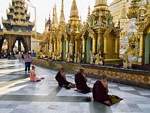 Praying Buddhist monks in Shwedagon Pagoda A nun and group of monks praying before idols in Myanmar.jpg