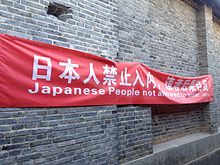 Anti-Japanese banner in Lijiang, Yunnan 2013. The Chinese reads "Japanese people not allowed to enter, disobey at your own risk." Anti-japanese banner Lijiang.jpeg