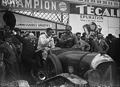 Photo d'un attroupement autour d'une voiture, le pilote est encore dans le cockpit.