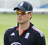 A man wearing an England cricket shirt, a cap and sunglasses