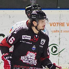 Joueur de hockey sur glace en gros plan, regardant le jeu à sa gauche.