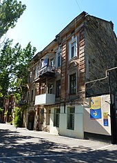 Three-storey building on a tree-lined city street