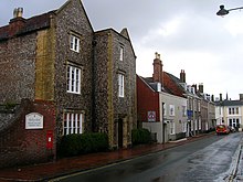 Photographie en couleurs d'un vieux bâtiment en briques situé le long d'une rue.