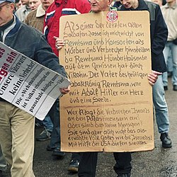 Fotografi av mennesker som demonstrerer mot utstilling om Wehrmacht i 2002. Utstillingen viste detaljer fra Wehrmachts krigsforbrytelser. En av plakatene har følgende innskrift: «Våre fedre var ikke kriminelle»