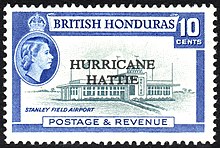 A rectangular postage stamp, denoting that the stamp is of the British Honduras and costs ten cents. In the center there is a picture of the terminal to Stanley Field Airport, with the words 'HURRICANE HATTIE' printed over it. At the bottom of the stamp reads 'Postage & Revenue'.