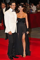 Red carpet fashion: Italian actors Gabriel Garko and Laura Torrisi wearing designer dress code, 2009. The male is in suit and female is wearing a gown.