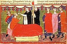 A crowned man lying in bed takes the Eucharist from two priest