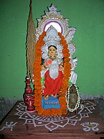 Alpana on an altar underneath a statue of the goddess Lakshmi