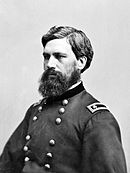 Black and white photo of a bearded man in a dark military uniform with the two stars of a major general on the shoulder tabs.