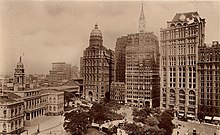Park Row buildings in the early 20th century (from bottom left clockwise) are: New York City Hall; the New York World Building, also known as the Pulitzer Building (with spherical top) which housed the New York World newspaper and is now the site of one of the Brooklyn Bridge entrance ramps; the New Yorker Staats-Zeitung (later demolished); the New York Tribune Building with the spire top, the present-day site of the Pace Plaza complex of Pace University); the New York Times Building, the 19th century headquarters of The New York Times and currently Pace University building; the American Tract Society Building, visible behind the Times Building; and, cut off from the picture, the Potter Building. ParkRow.jpg