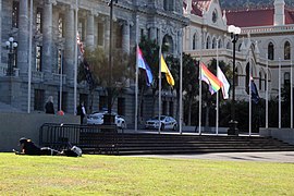 Banderas LGBT junto a la bandera nacional en el Parlamento de Nueva Zelanda al comienzo de la Conferencia Mundial de ILGA 2019. Iban a media asta, en homenaje por los atentados de Christchurch de 2019