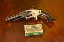 A Smith & Wesson Model 1, 2nd issue; a two patent date variety shown next to a period box of .22 Short black powder cartridges Smith & Wesson Model 1, 2nd Issue.jpg