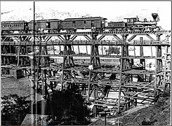 The "Reno" pulling the Lightning Express over the Crown Point Trestle, at Gold Hill, Nevada, on its way to Carson City in the 1870s. The trestle was built in 1869, and last until 1936.