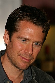 Alexis Denisof interprète Sandy Rivers.