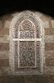 One of the windows of coloured glass set into a stucco grille.