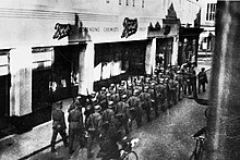 German soldiers marching before a Boots pharmacy in the British Channel Islands, 1940s German soldiers in British Channel Islands 1940s.jpg