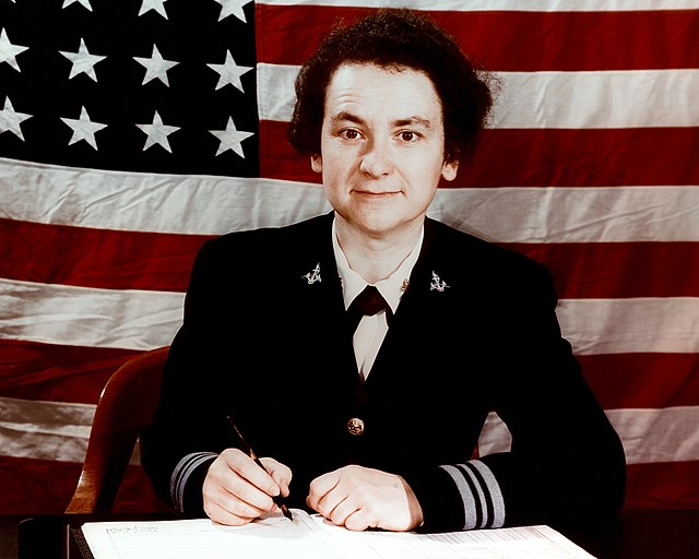 Female WAVE officer sitting at her desk in dress blue uniform