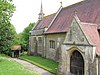 Part of a church built in stone with red tiles and a short spire