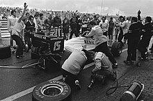 Photo en noir et blanc de personnes autour d'une voiture de Formule 1