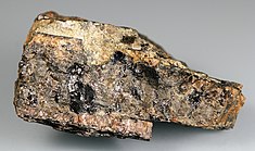 Ukázka hnědočerveně zbarveného minerálu britolitu-(Y) ve vzorku společně s yttralitem-(Y) a formanitem-(Y) z lokality Lövböle ve Finsku