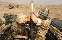 Two soldiers with a mortar gun--one loading and the other aiming