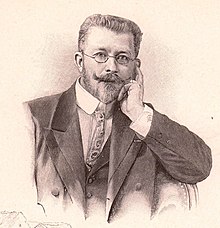Jules-Alexis Muenier. Zeichnung in Sepia. Ein Mann mit Bart und gezwirbeltem Schnurrbart und kleiner runder Brille in Denkerpose mit der linken Hand an der Backe.