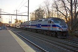 A MARC Penn Line train pulls out of Odenton station while an Northeast Regional train pulled by an AEM-7 passes through.