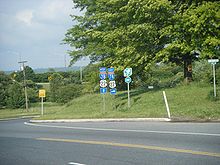 A three-lane surface road at an interchange with an Interstate highway. A set of signs on the right side of the road reads west Interstate 78 U.S. Route 22 straight ahead, east Interstate 78 U.S. Route 22 right, and New Jersey Turnpike right