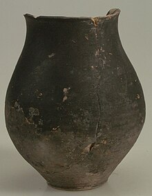 Photographie d'un pot à panse longue, en céramique noire.