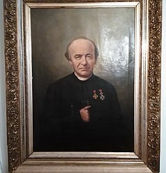 Portretschilderij dat Guido Gezelle voorstelt, met zijn eretekens (olieverf op doek, 110 cm × 85 cm). Het werd in 1902 vervaardigd door het atelier van Hubertus Alouisius Henricus Maria Bogaerts (Hubert Bogaerts) in Brussel (Société Belge des Portraits Bogaerts) en werd rechtsonder gesigneerd met Bogaerts Bruxelles.