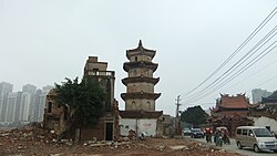 Pagoda Putih yang masih ada (tengah) di Kuil Shuixin Chan (kanan), dengan lingkungan pemukiman lama di dekatnya (kiri) dihancurkan, untuk membuka jalan bagi pembangunan baru (seperti terlihat di latar belakang)