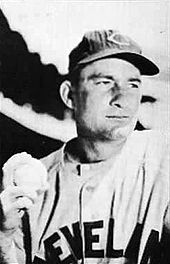 A baseball player is shown his chest up, holding a baseball with his right hand.