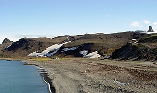 Blick vom Ufer der Admiralty Bay auf die Rescuers Hills mit der US-amerikanischen Pieter-Lenie-Station (vorne), dem Sphinx Hill (links) und dem Pawson Peak (rechts)