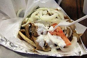 A gyro sandwich with meat, onions, tomato, and...