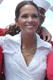 Head and shoulders shot of a smiling Berry with dark hair pulled back, wearing a lace shirt and turquoise necklace.