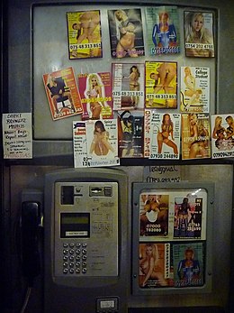 L'intérieur d'une cabine téléphonique londonienne est couvert d'autocollants promotionnels pour des services de téléphonie rose.