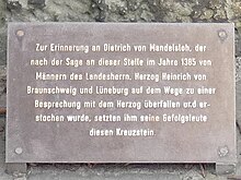 Tafelinschrift: Zur Erinnerung an Dietrich von Mandelsloh, der nach der Sage an dieser Stelle im Jahre 1385 von Männern des Landesherrn, Herzog Heinrich von Braunschweig und Lüneburg auf dem Wege zu einer Besprechung mit dem Herzog überfallen und er- stochen wurde, setzten ihm seine Gefolgsleute diesen Kreuzstein.