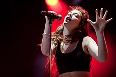 Lorde performing holding a mic.