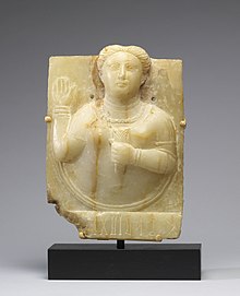 Sculpture of a Sabaean priestess raising her hand to intercede with the sun goddess on behalf of a donor. Probably first century. South Arabian - Stele with a Female Bust - Walters 2173.jpg