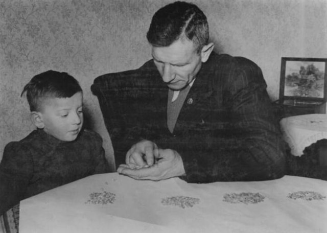 Photo en noir et blanc montrant un enfant et un homme assis à une table